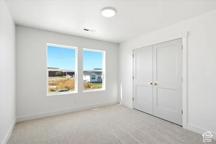 Neutral-toned carpeting, dual-pane windows, and white interior doors with brass-tone hardware