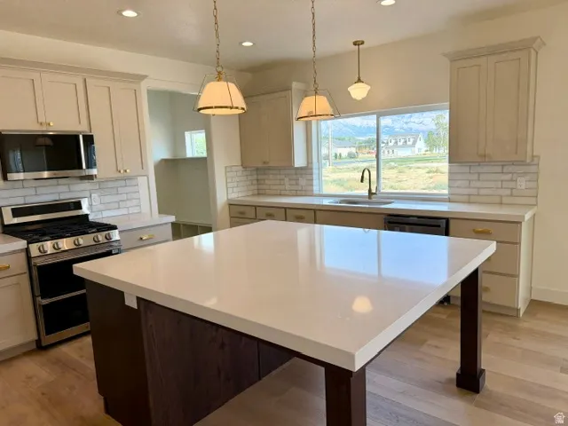 Kitchen featuring a large central island with solid surface countertop, stainless steel appliances, subway tile backsplash, and recessed lighting