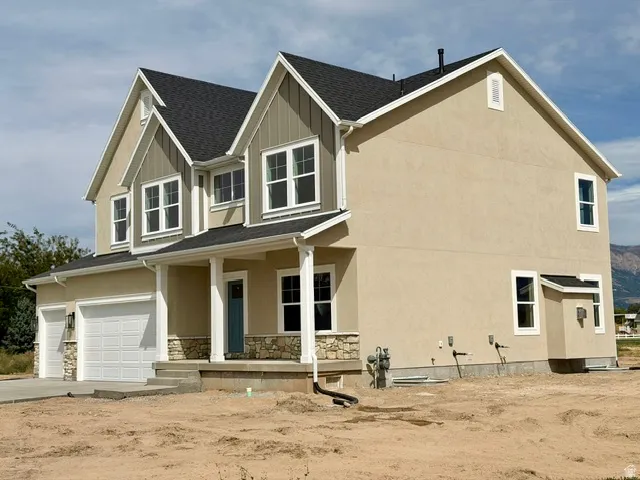 Newly constructed two-story Colonial featuring a cream exterior with dark architectural shingles, white trim detailing, and a front-facing gable with paired windows