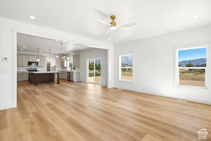 Open-concept area featuring wood-finish flooring, recessed lighting, a ceiling fan, and large windows with mountain scenery