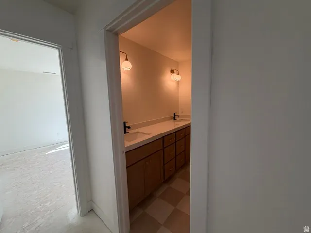 Dual vanity with a light-toned countertop, wood-finish cabinetry, and matte black fixtures