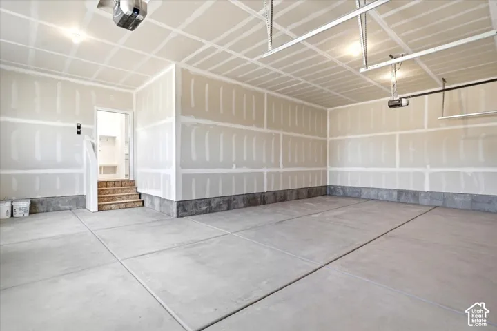 Multi-car garage featuring concrete flooring, taped drywall, overhead automatic garage door openers, and a built-in step entry