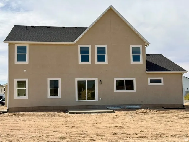 Stucco exterior with multiple windows, a sliding glass door, and a concrete patio