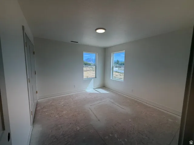 Neutral painted walls, dual windows, flush-mount ceiling light, and panel doors
