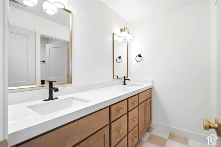 Double vanity featuring wood-finish cabinetry, quartz countertops, dual rectangular undermount sinks, matte black faucets, and brass-tone hardware