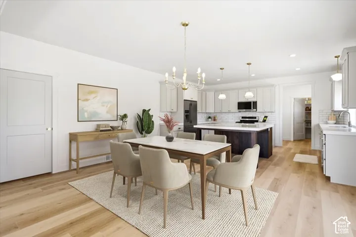 Open-concept kitchen and dining area featuring wood-finish flooring, a central kitchen island with seating, shaker-style cabinetry, and subway tile backsplash