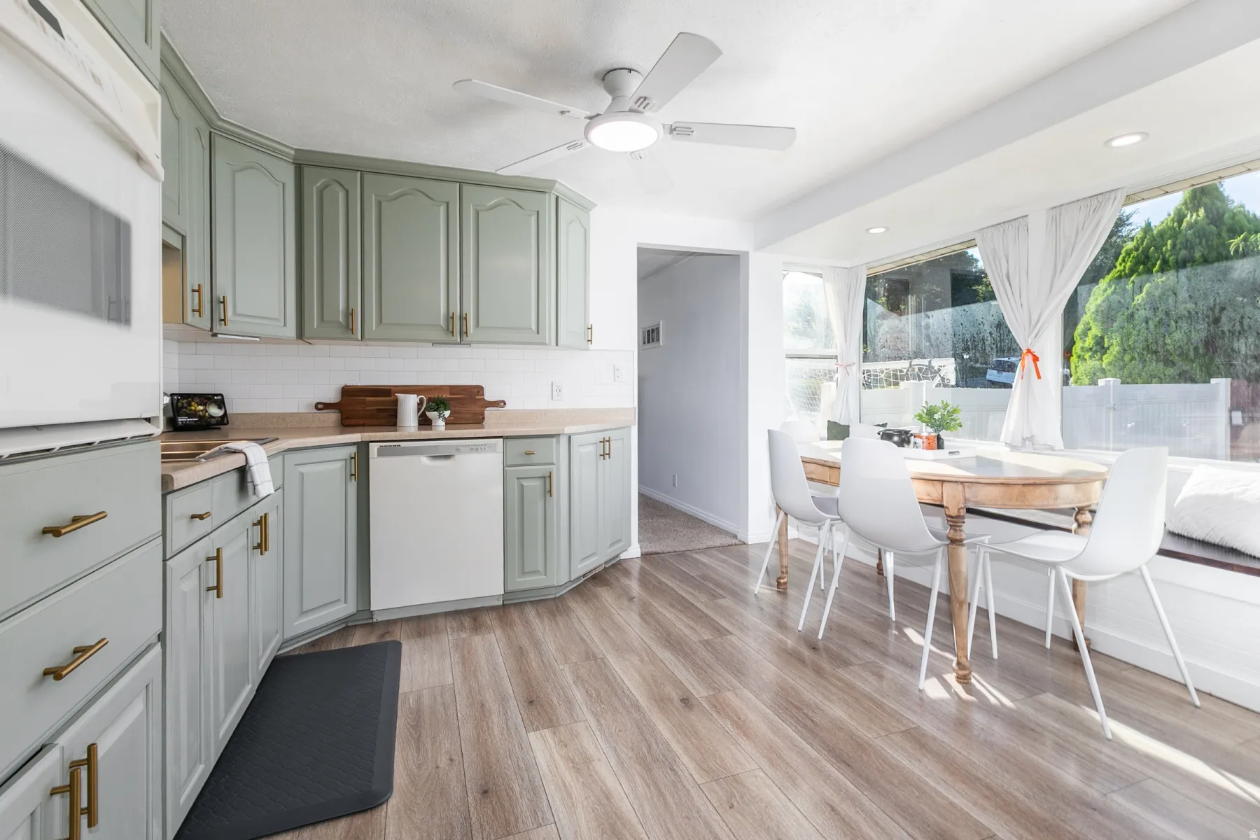 Kitchen featuring light green cabinetry, gold-tone hardware, wood-finish flooring, and a built-in window seat