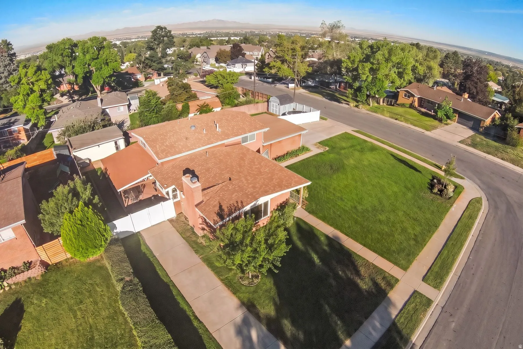 Expansive front yard with a large lawn and mature trees, brick exterior, and a paved driveway