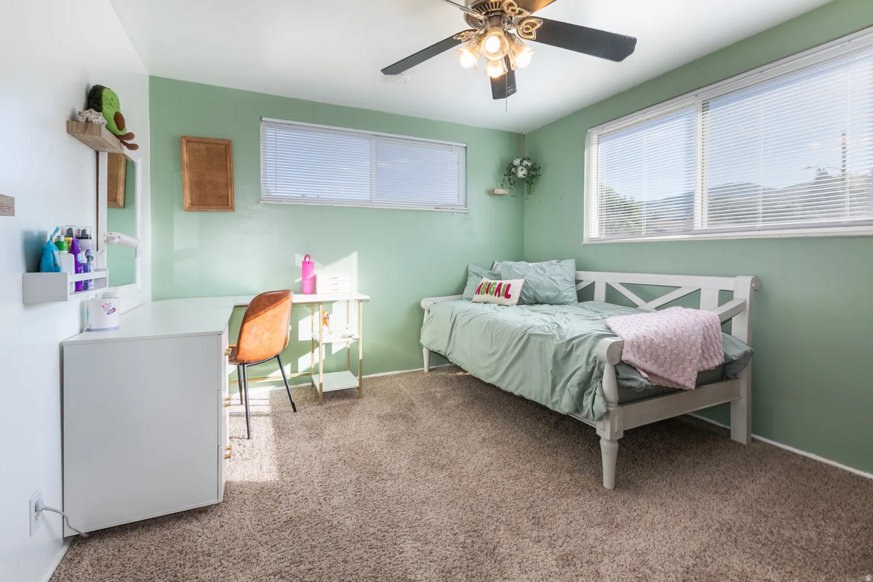 Wall-to-wall carpeting with a ceiling fan light fixture, expansive windows, and a built-in desk
