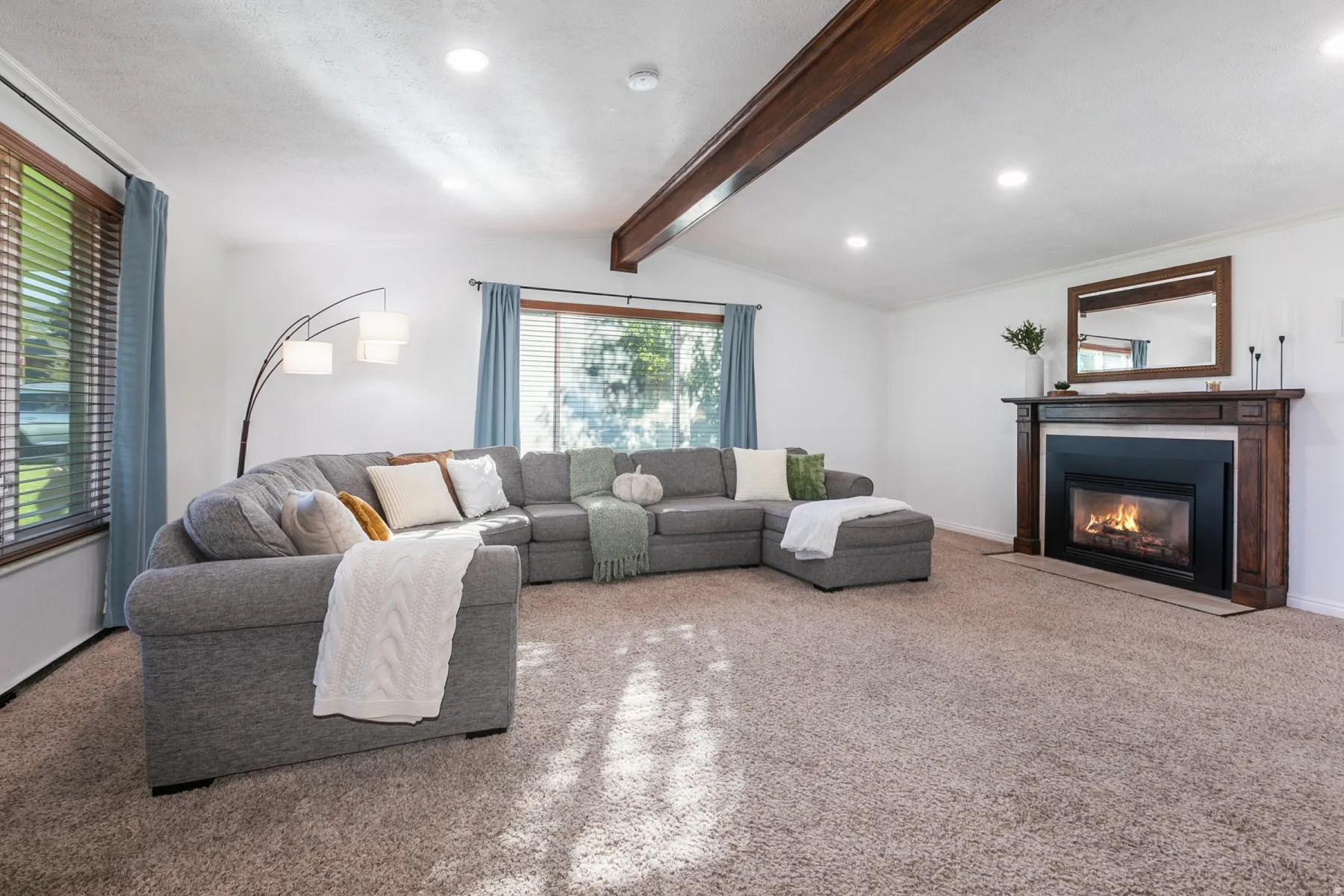 Wood-finish ceiling beam, recessed lighting, and a fireplace with a wood mantle and surround