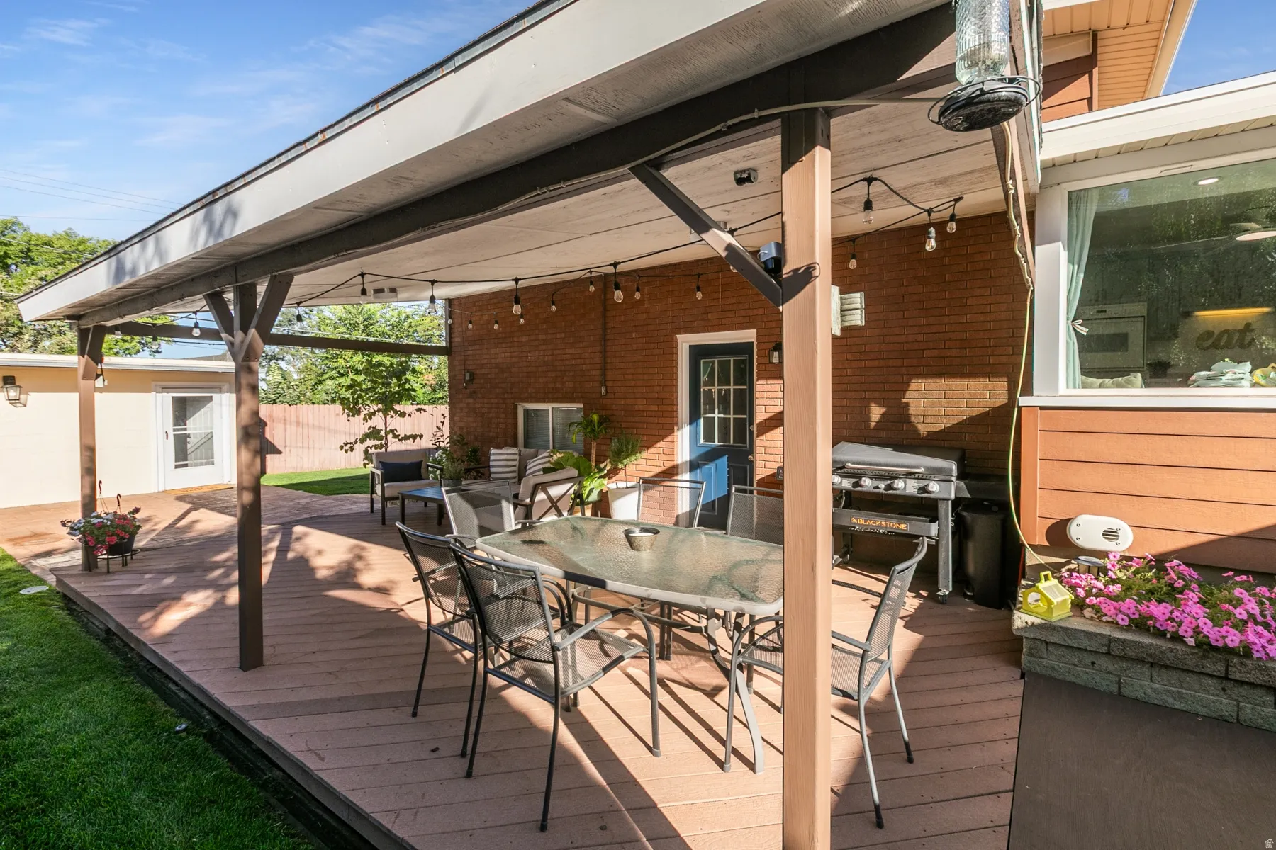 Spacious outdoor deck with a covered area, brick exterior, and a separate structure