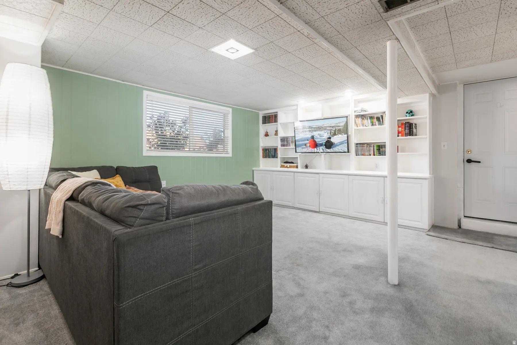Recessed lighting, drop ceiling, wall-mounted television, built-in shelving, built-in cabinetry