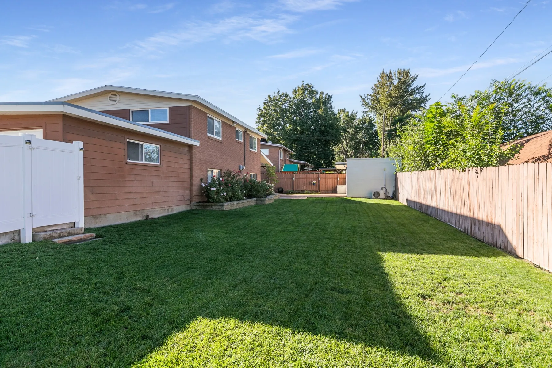 Expansive grassy yard with wood fencing and a white vinyl fence section