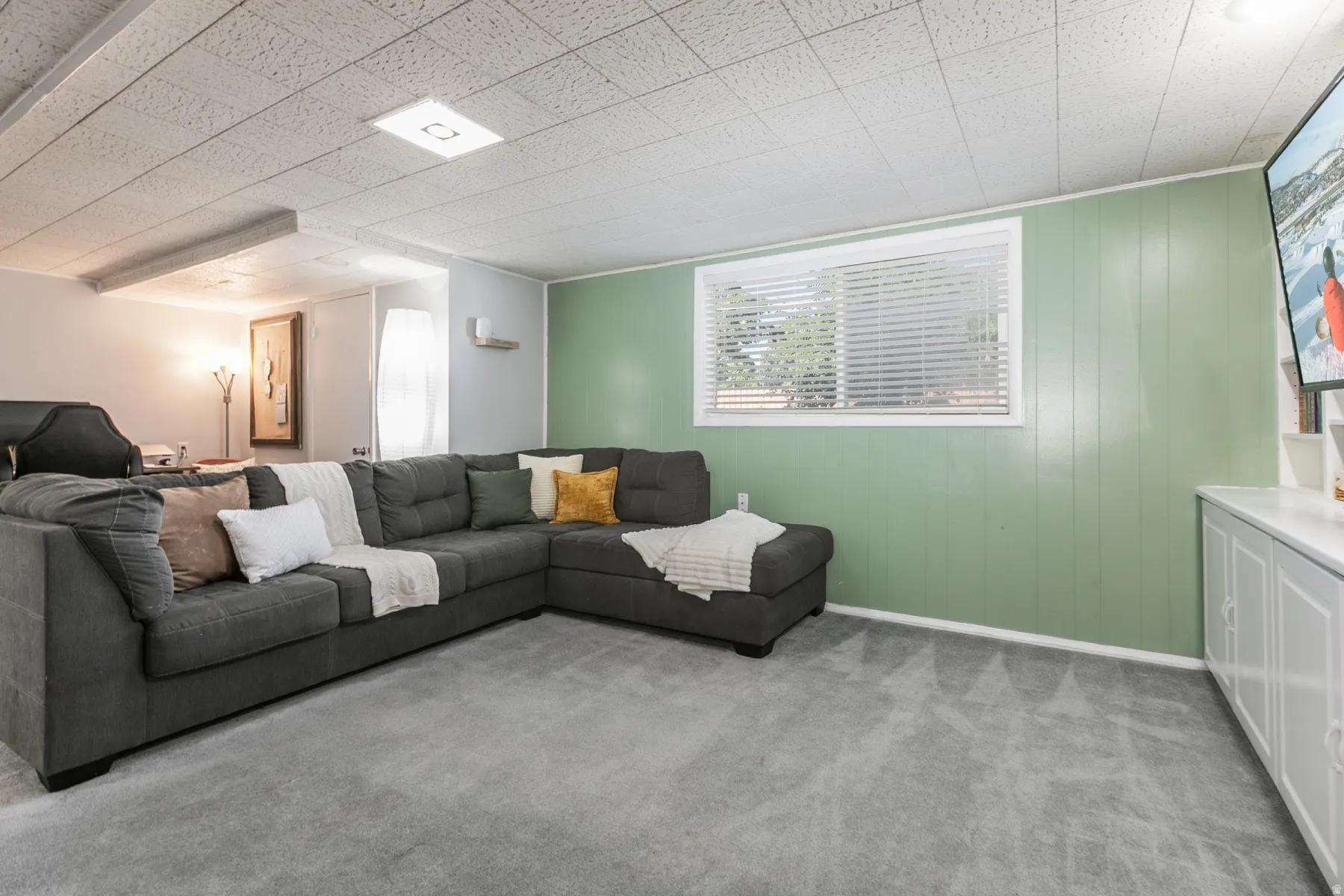 Recessed lighting, light-toned carpeting, built-in white cabinetry, a window with blinds, and paneled wall accents