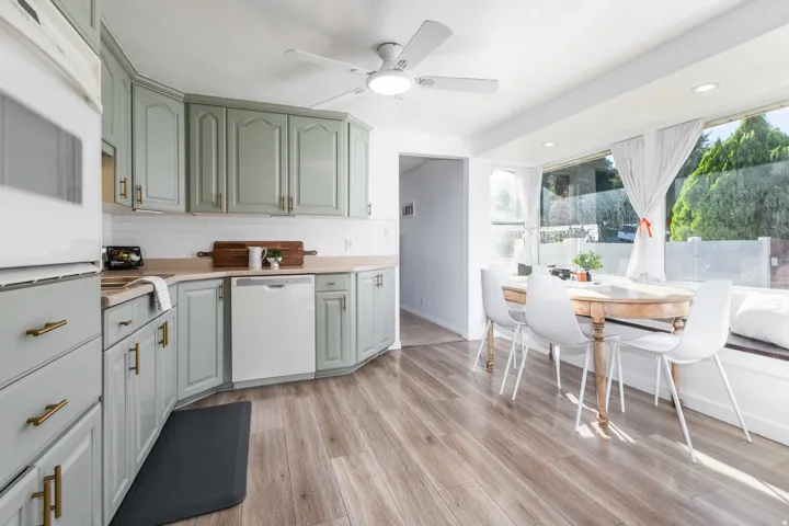 Kitchen featuring light green cabinetry, gold-tone hardware, wood-finish flooring, and a built-in window seat