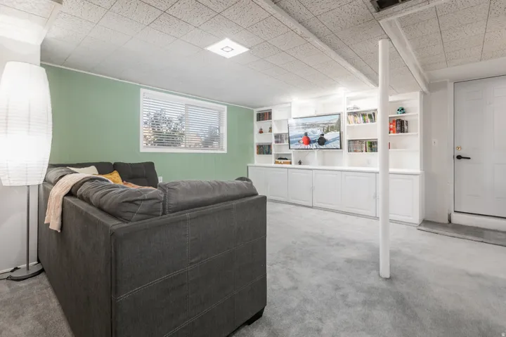 Recessed lighting, drop ceiling, wall-mounted television, built-in shelving, built-in cabinetry