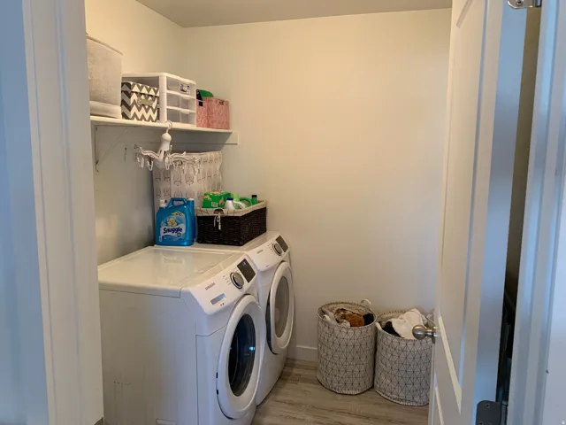 Dedicated laundry area featuring a built-in shelf and wood-finish flooring