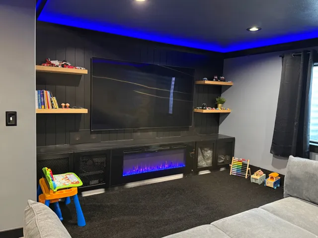 Built-in media console with integrated electric fireplace, floating shelves, recessed ceiling lighting, and accent cove lighting