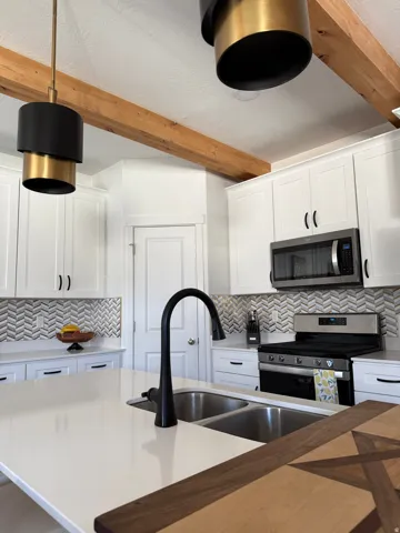 White shaker cabinetry, light-toned countertops, and a herringbone tile backsplash