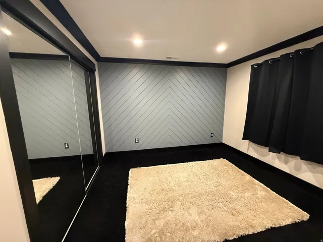 Feature wall with chevron paneling, recessed lighting, mirrored closet doors, and dark trim details