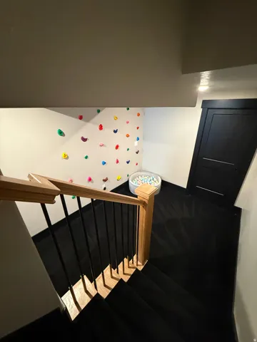 Hardwood handrail with black metal balusters, dark wood-finish flooring, and white painted walls