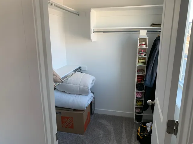 Closet space featuring hanging rods, an upper shelf, and carpeting