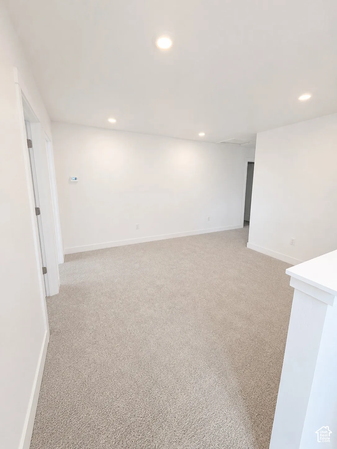 Recessed lighting, light-toned carpet, white walls, and a white door frame