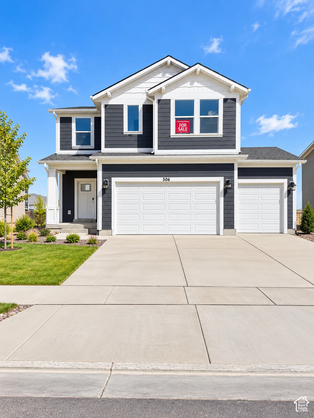 Two-story exterior with dark gray siding and white trim, featuring a three-car garage