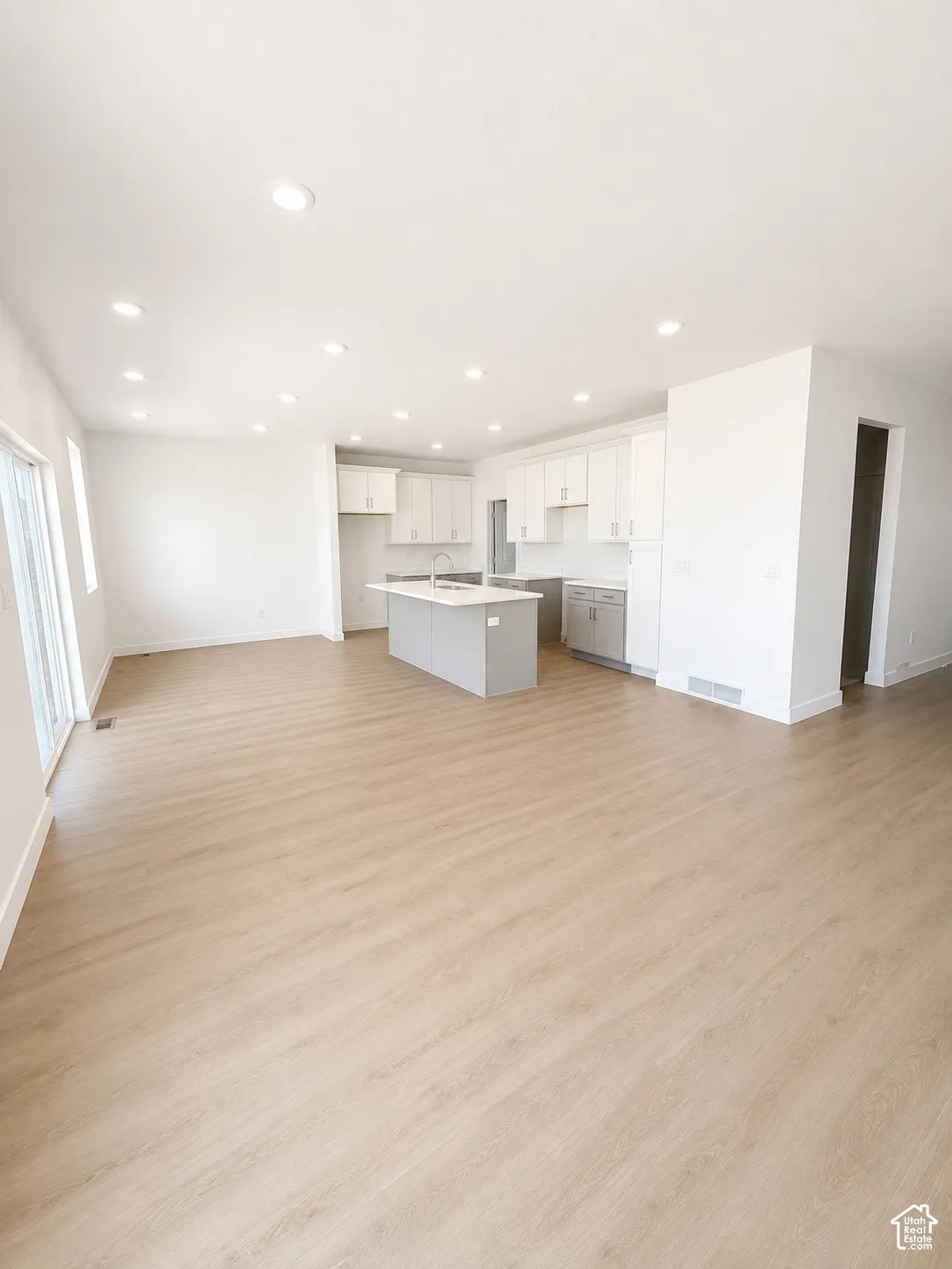 Open-concept living space featuring wood-finish flooring, recessed lighting, and a kitchen with an island, light cabinetry, and stainless steel appliances