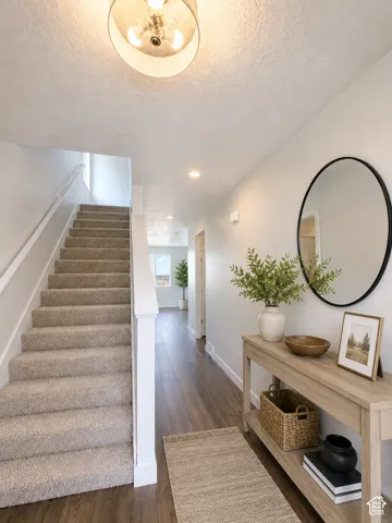 Carpeted staircase with white handrail, wood-finish flooring, recessed lighting, and a drum-style semi-flush mount ceiling light