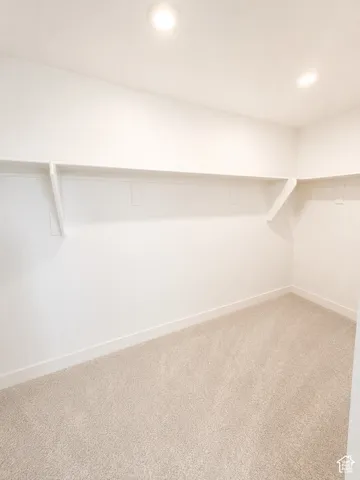 Recessed lighting, wall-mounted shelving, neutral-toned carpeting, and white walls