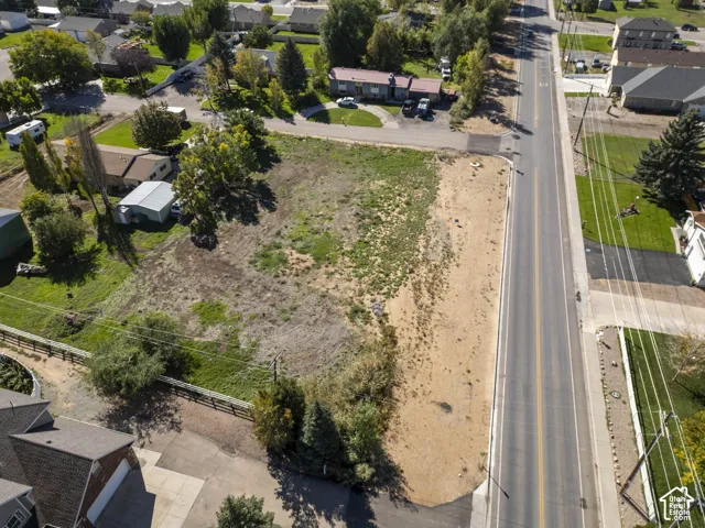 Expansive vacant land parcel featuring a paved road frontage, established fencing, and visible utility poles