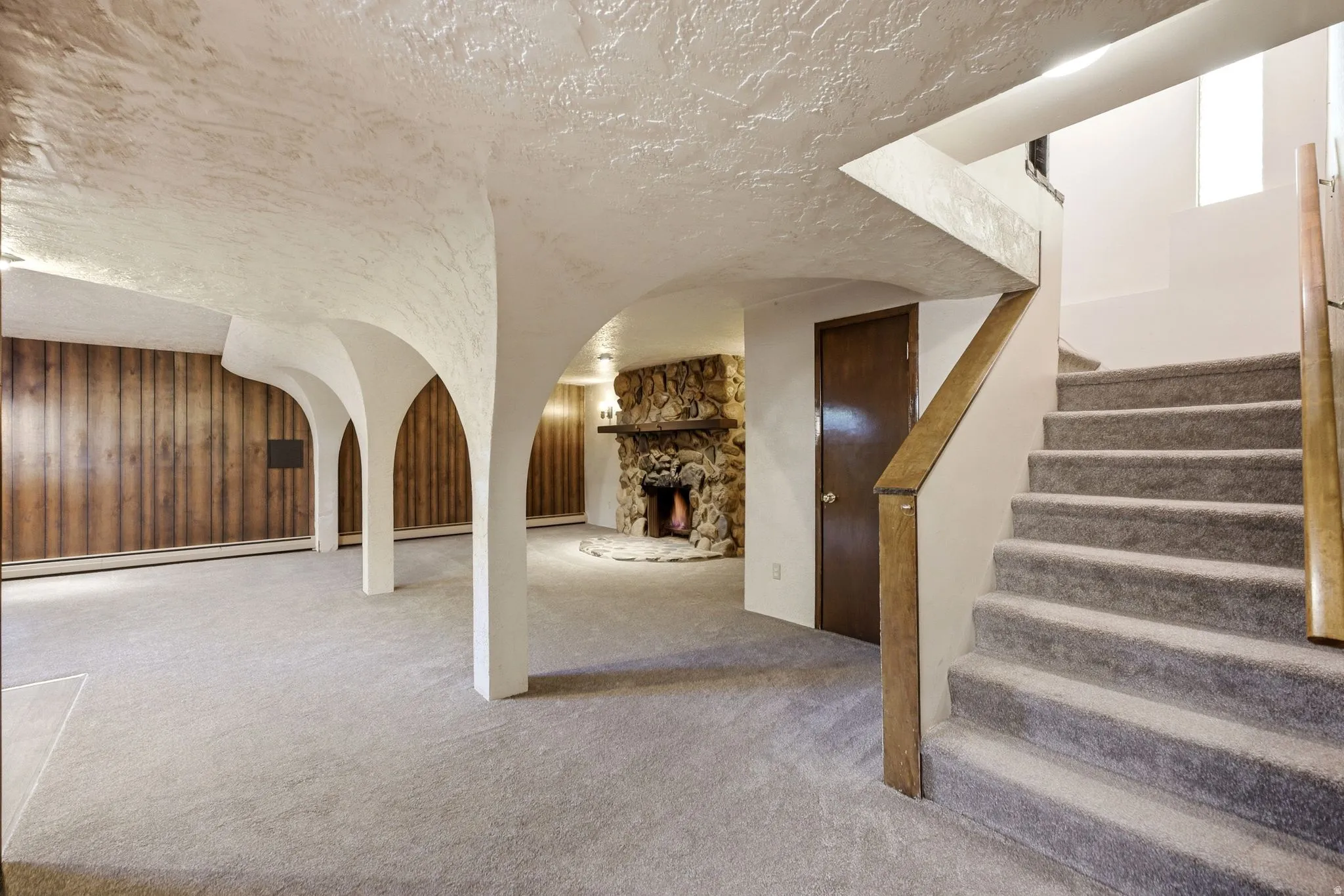 Spacious carpeted area with decorative archways and wood paneling