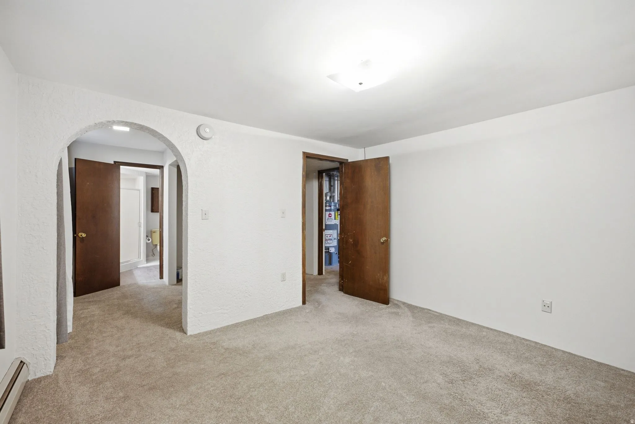 Carpeted room featuring an arched doorway and a flush-mount ceiling light