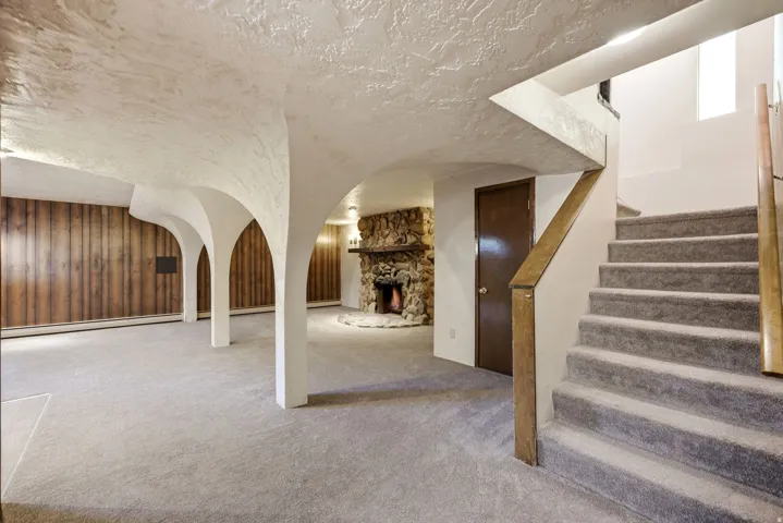 Spacious carpeted area with decorative archways and wood paneling