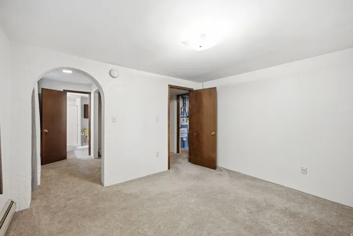 Carpeted room featuring an arched doorway and a flush-mount ceiling light