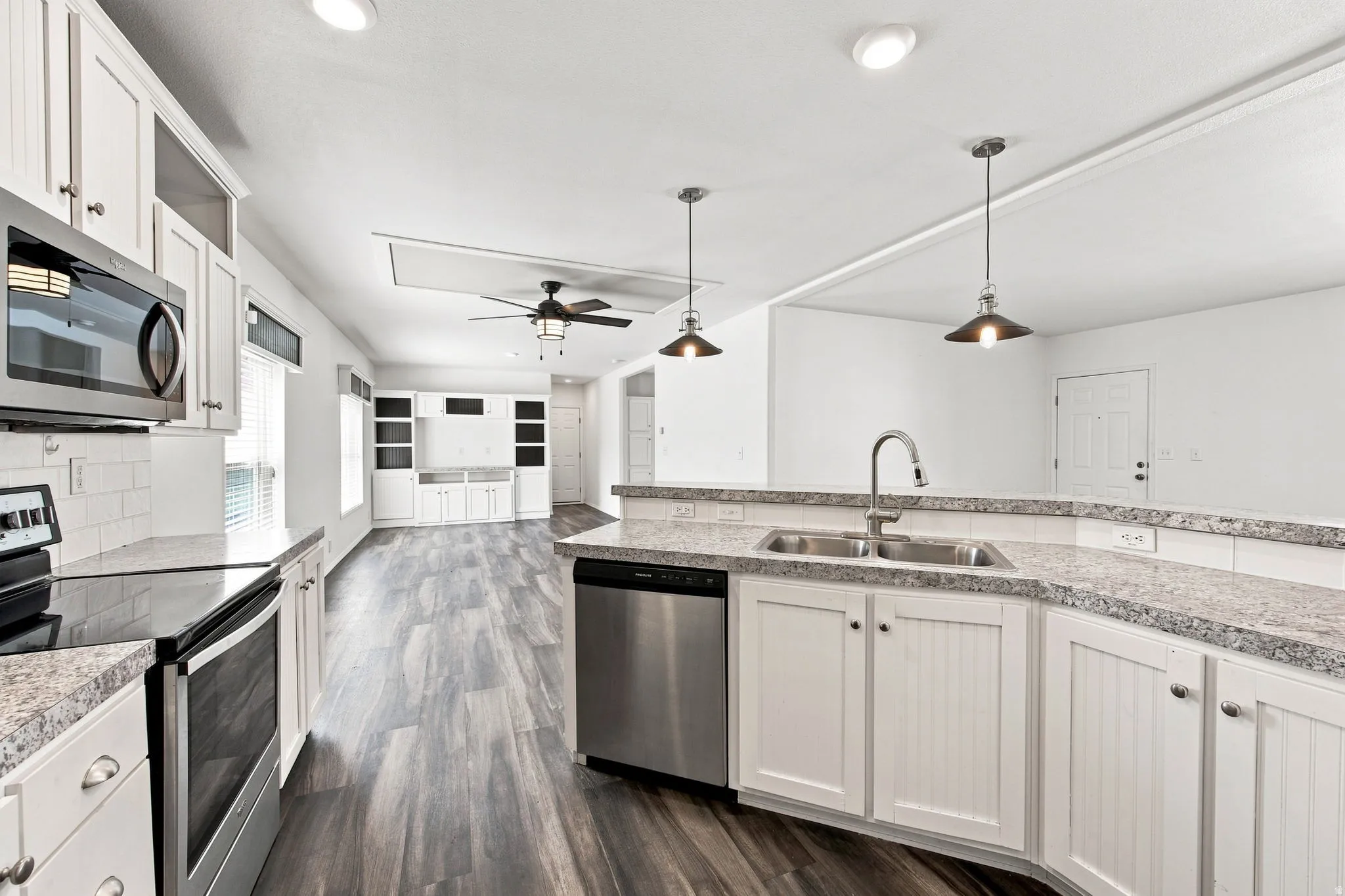 White shaker-style cabinetry with chrome hardware, wood-finish flooring, recessed lighting, and stainless steel appliances
