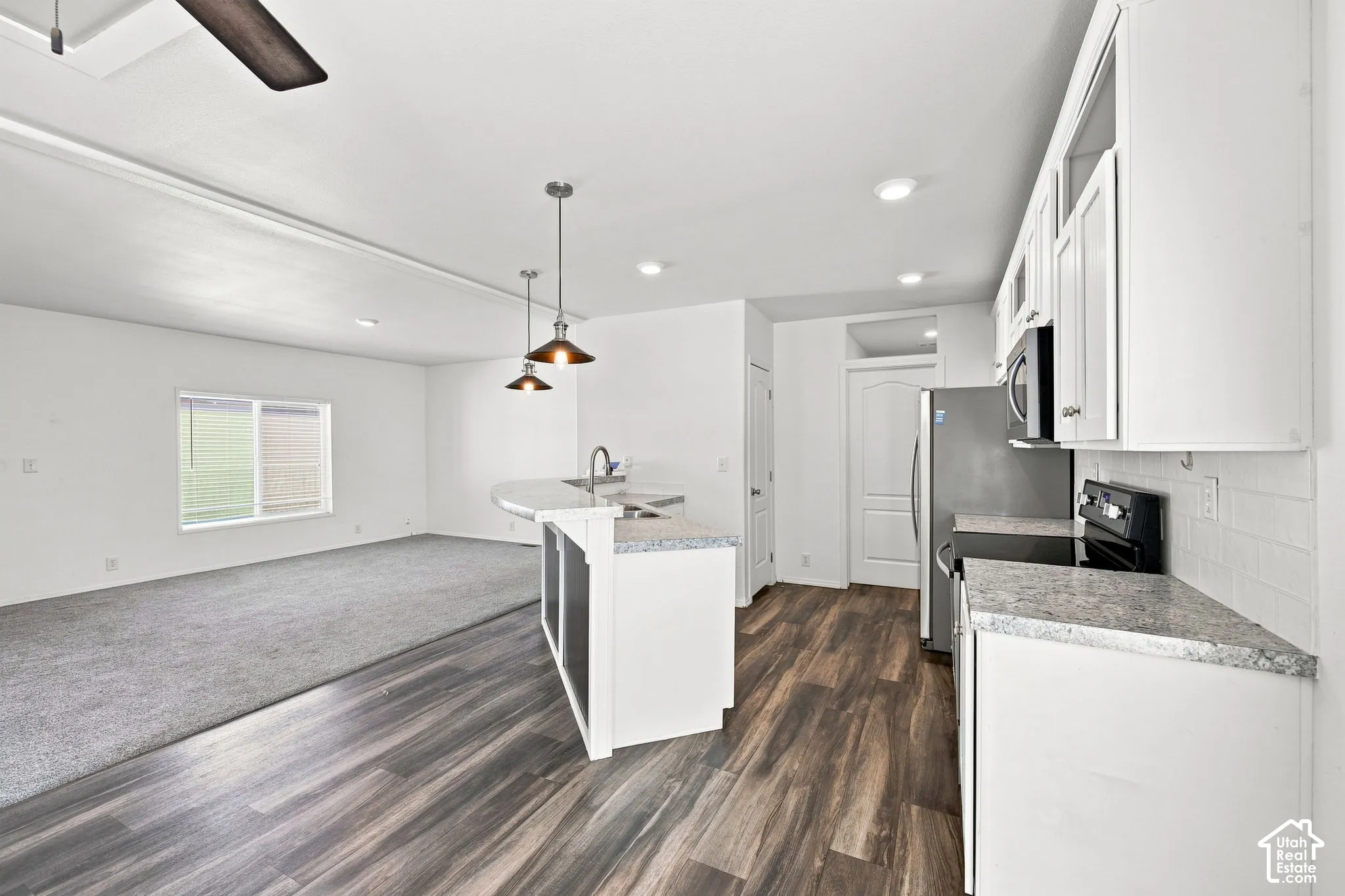Kitchen featuring white cabinetry, light countertops, wood-finish flooring, and stainless steel appliances