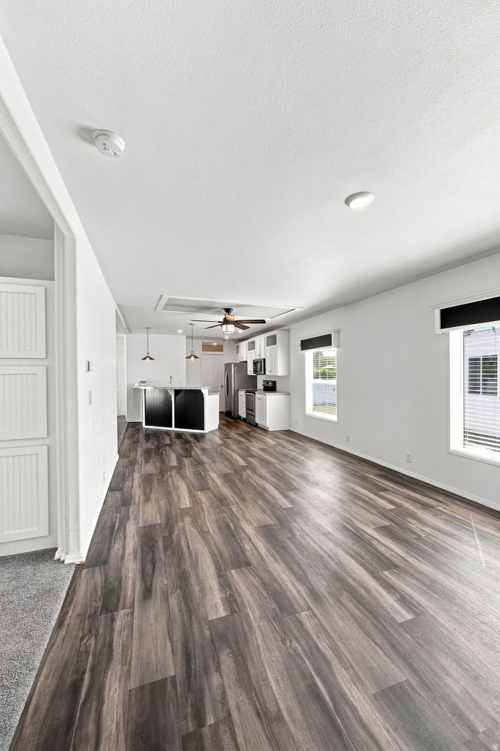 Open-concept living space featuring wood-finish flooring, white walls, and recessed lighting