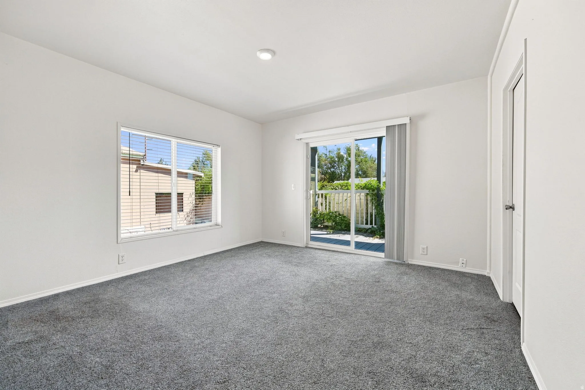 Bright, light-filled bedroom featuring neutral wall finishes, recessed ceiling lighting, and plush carpeting throughout