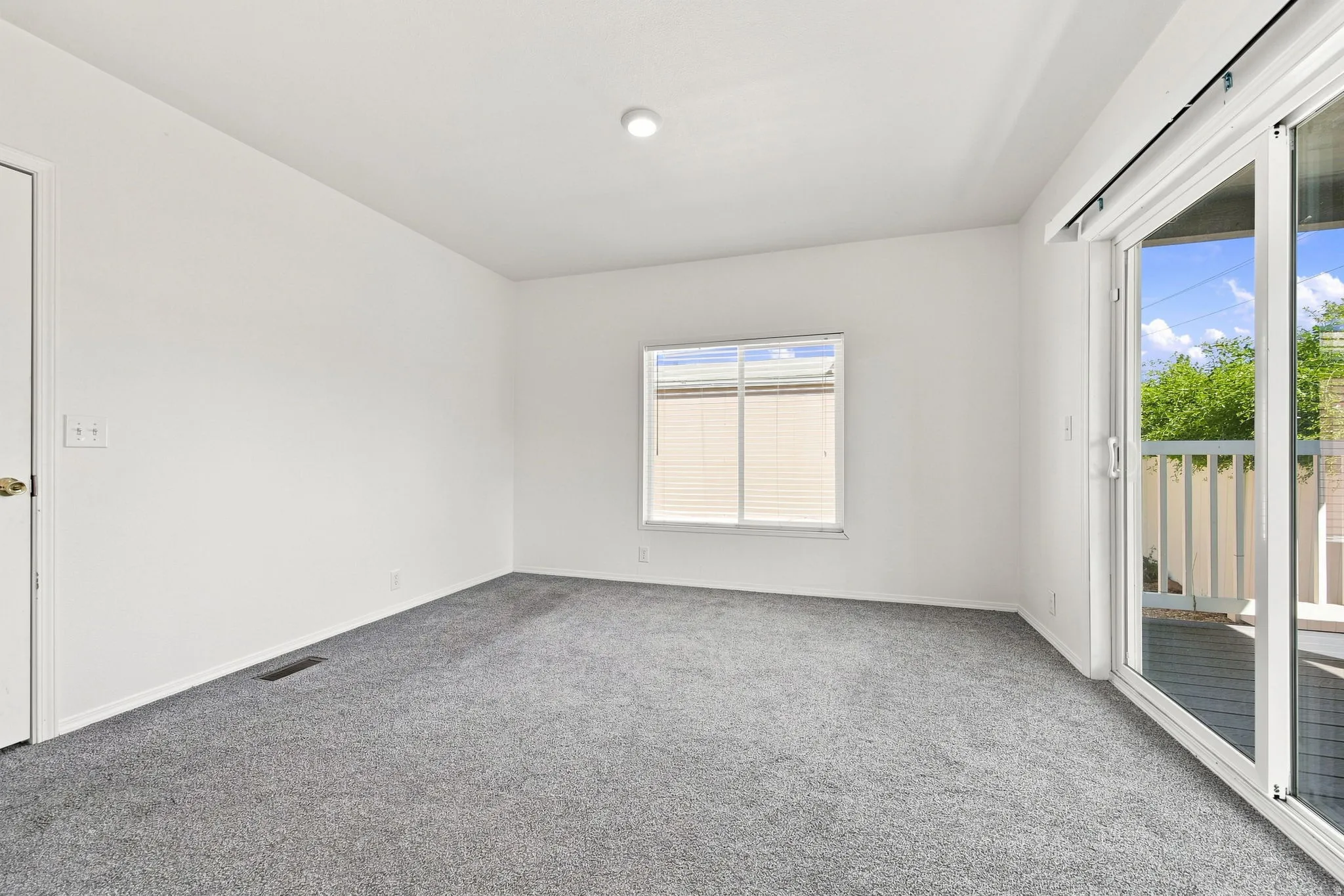Plush carpeting, a large window, and sliding glass doors to the exterior balcony