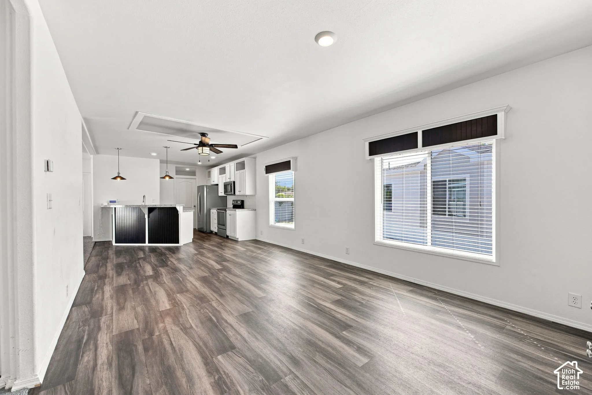Spacious interior with wood-finish flooring, white walls, and a ceiling fan