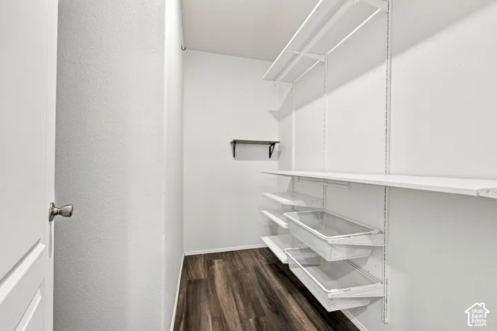 Wood-finish flooring, white walls, built-in shelving system, sliding storage bins, and a wall-mounted floating shelf