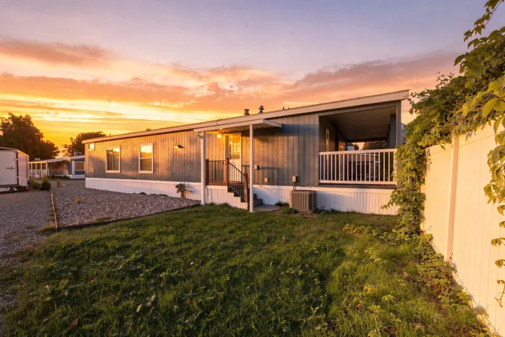Modern manufactured home with metal exterior siding and expansive covered front porch featuring white railings