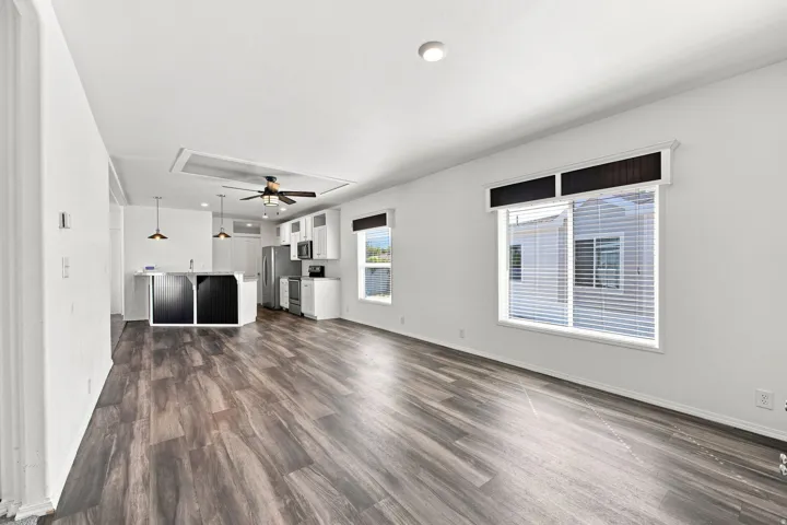 Spacious interior with wood-finish flooring, white walls, and a ceiling fan