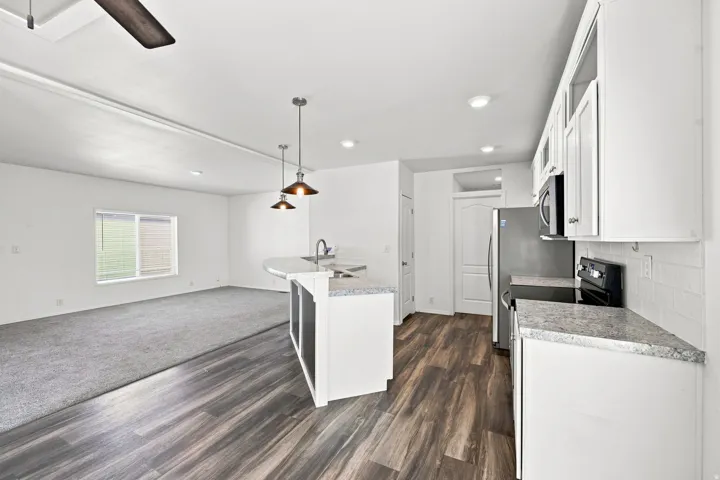 Kitchen featuring white cabinetry, light countertops, wood-finish flooring, and stainless steel appliances