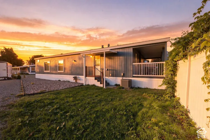 Modern manufactured home with metal exterior siding and expansive covered front porch featuring white railings