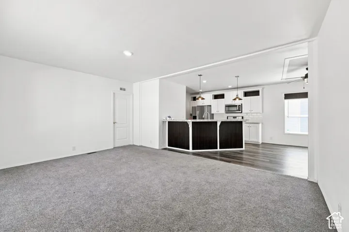 Open-concept living space with gray carpeting, white walls, and recessed lighting
