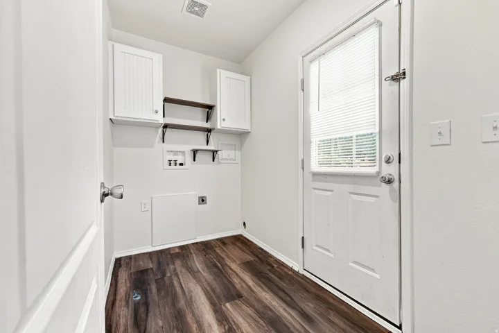 Laundry area featuring wood-finish flooring, white paneled cabinetry, and built-in shelving