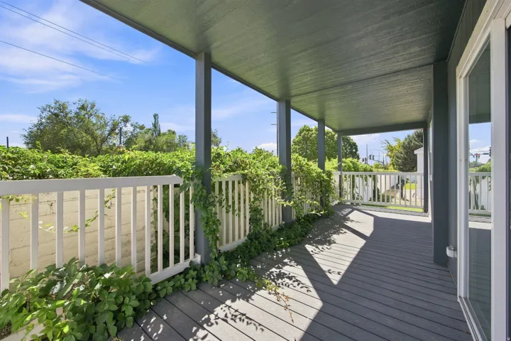 Covered porch with composite decking, white railing, and sliding glass door
